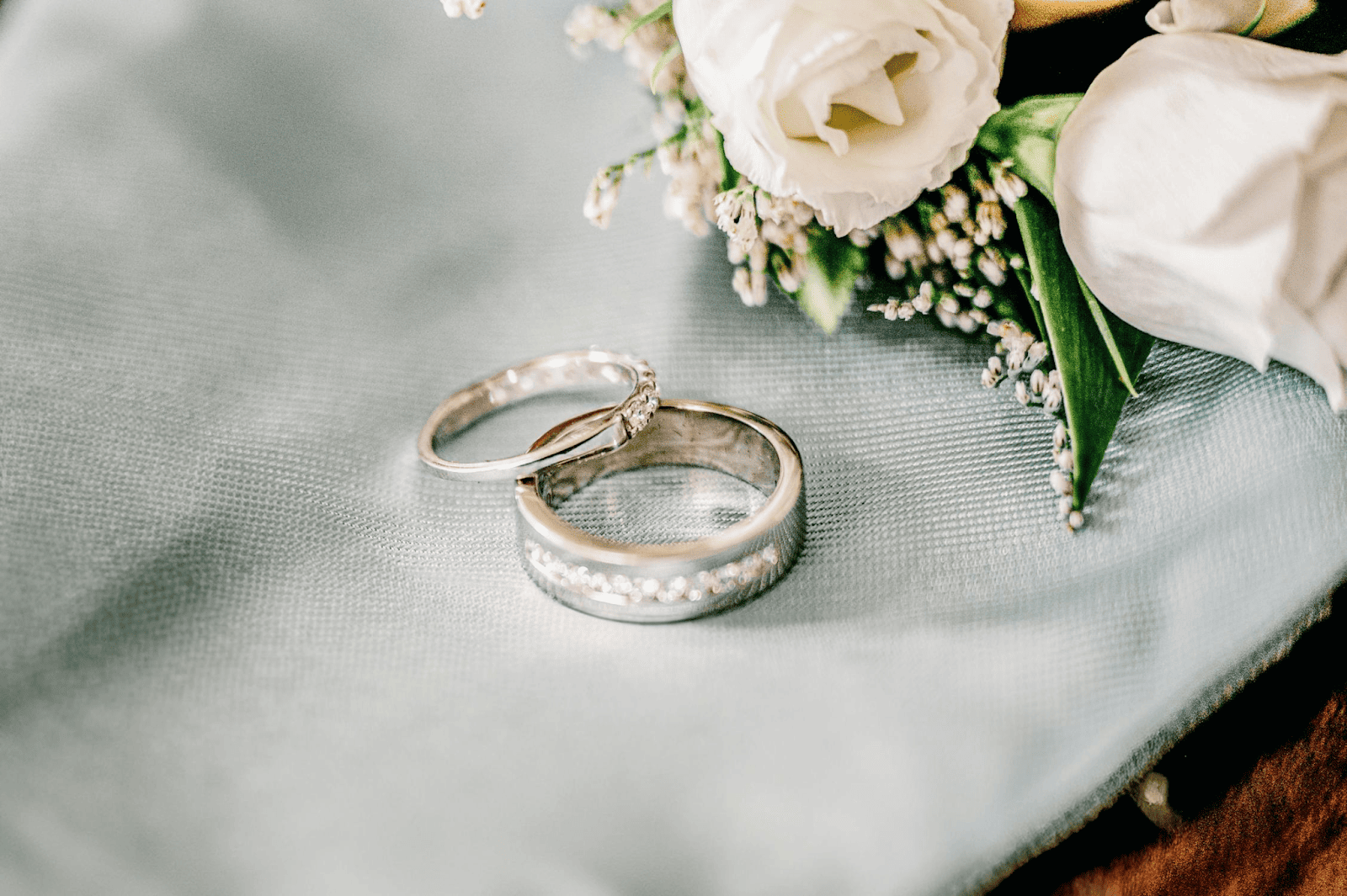 Wedding bands on a white back drop with white roses